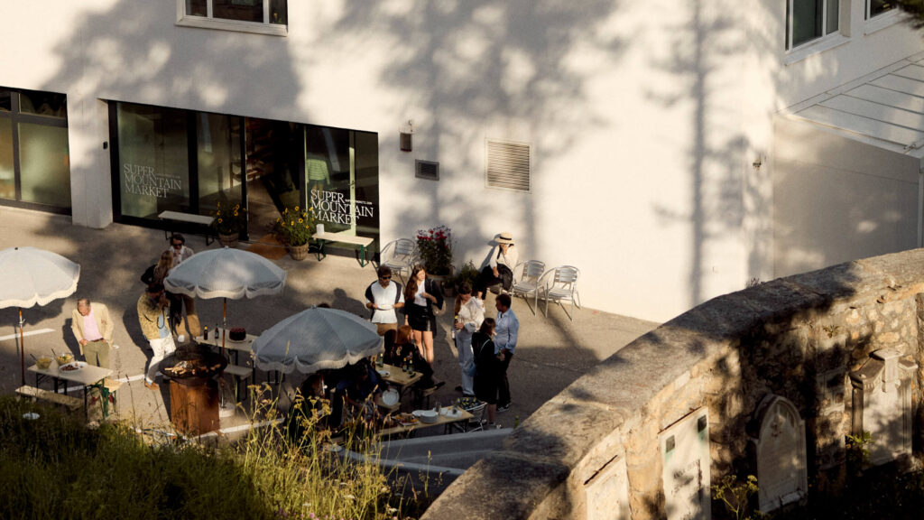 A group of people is standing on the terrace infront of the Super Mountain Market.
